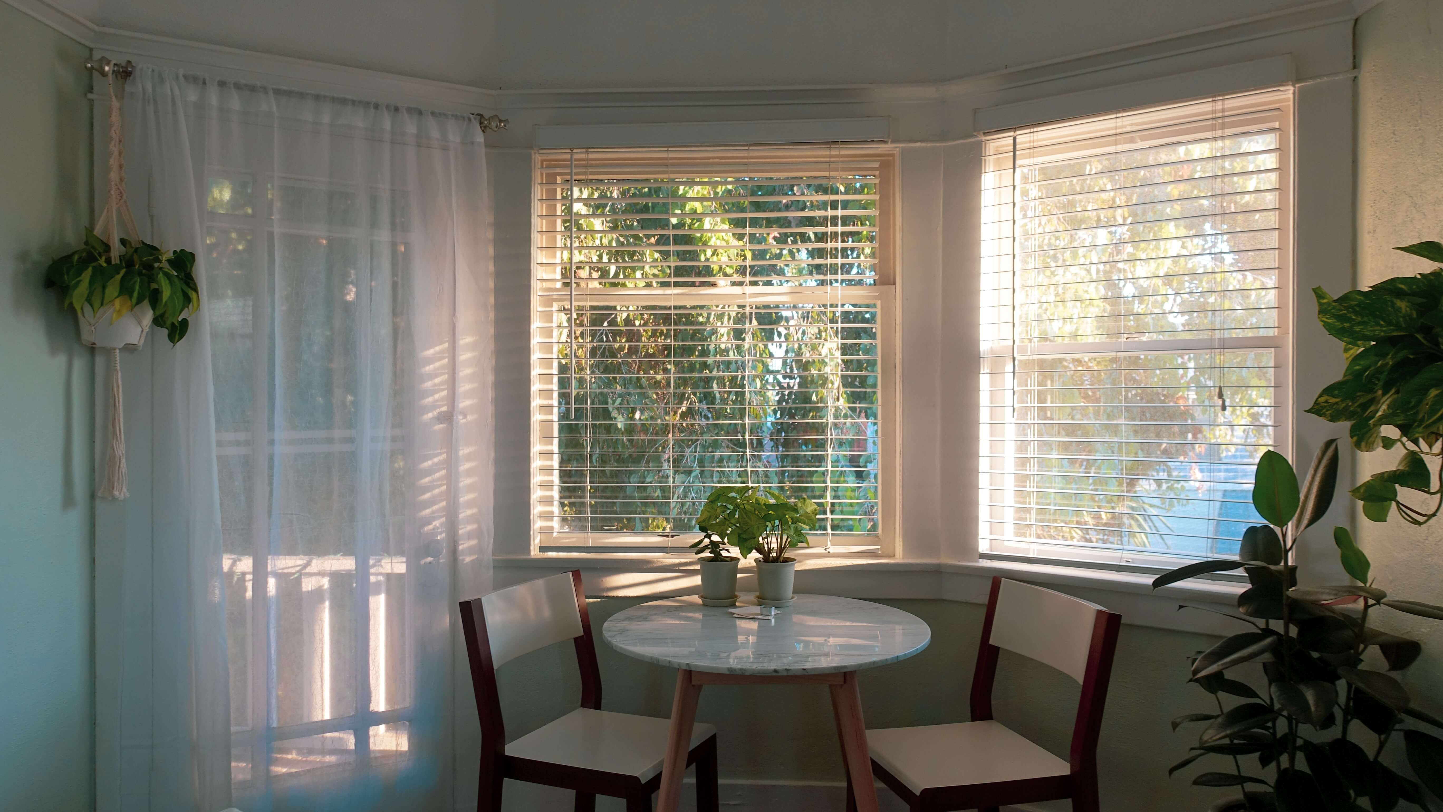 bay windows with wood blinds and sheer curtains