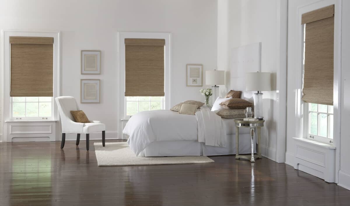bedroom with all white interior design, tan accent pillows, and tan bamboo blinds