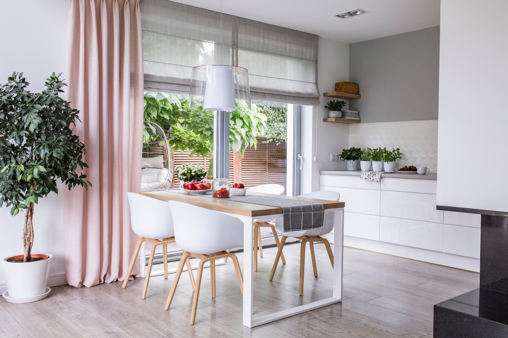 pink drapes and gray Roman shades in a kitchen with a sliding glass door