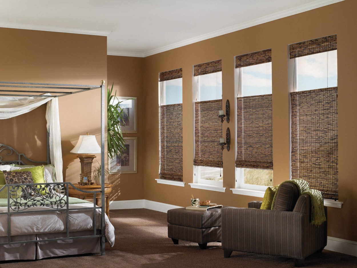 formal bedroom with four poster bed and woven wood blinds