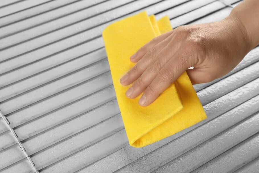 Hand with cloth wiping clean dirty blinds