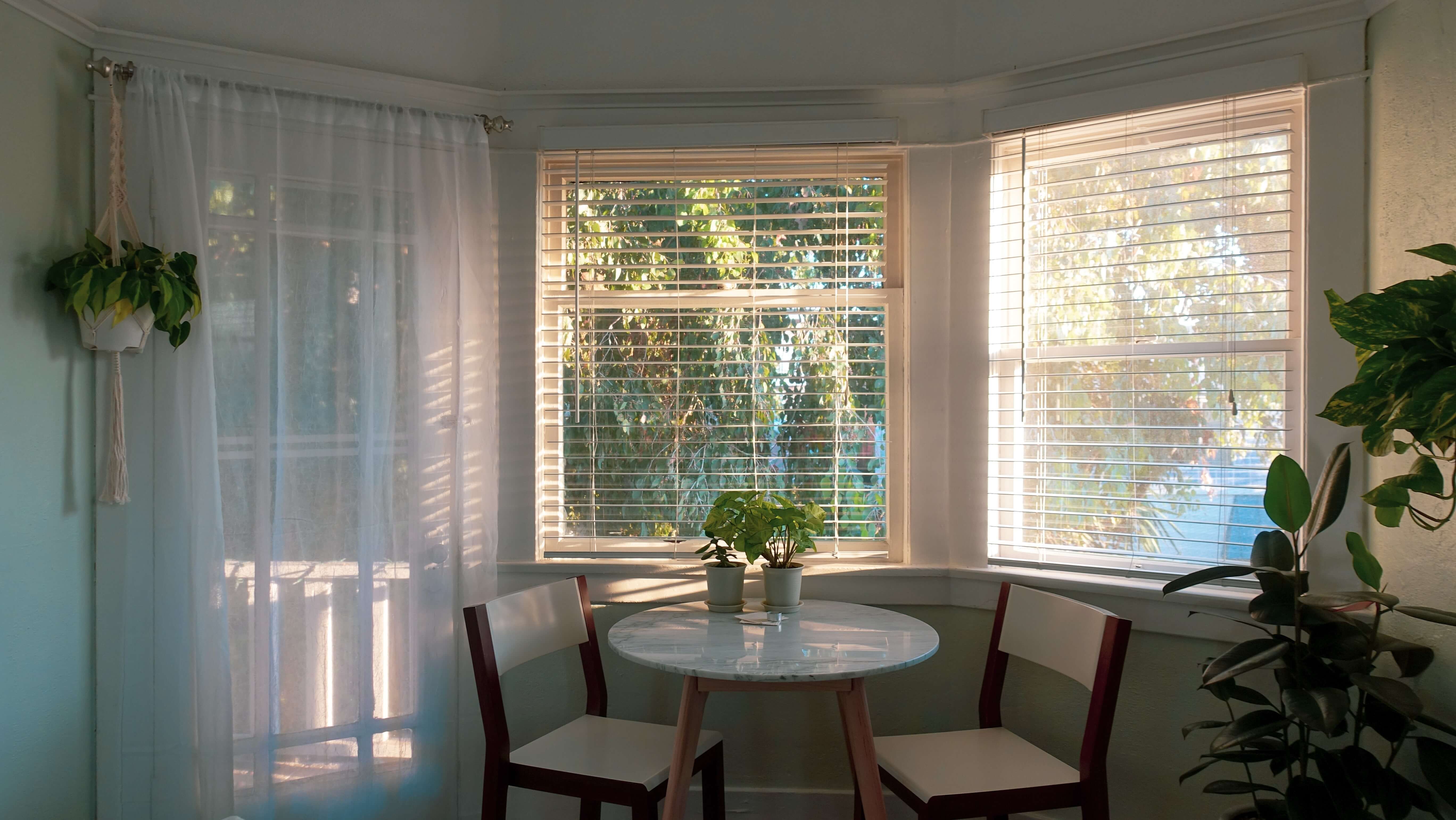 sheer panel over french door next to windows with wood blinds
